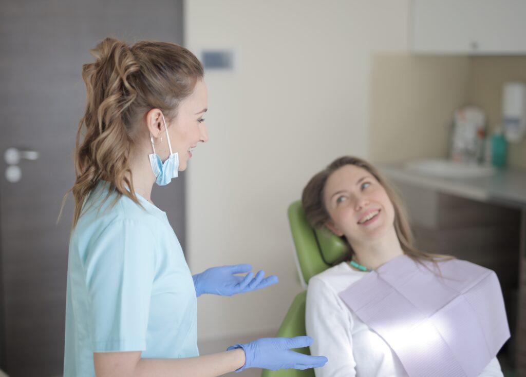 A young woman in a dentist's chair smiling at a female dentist